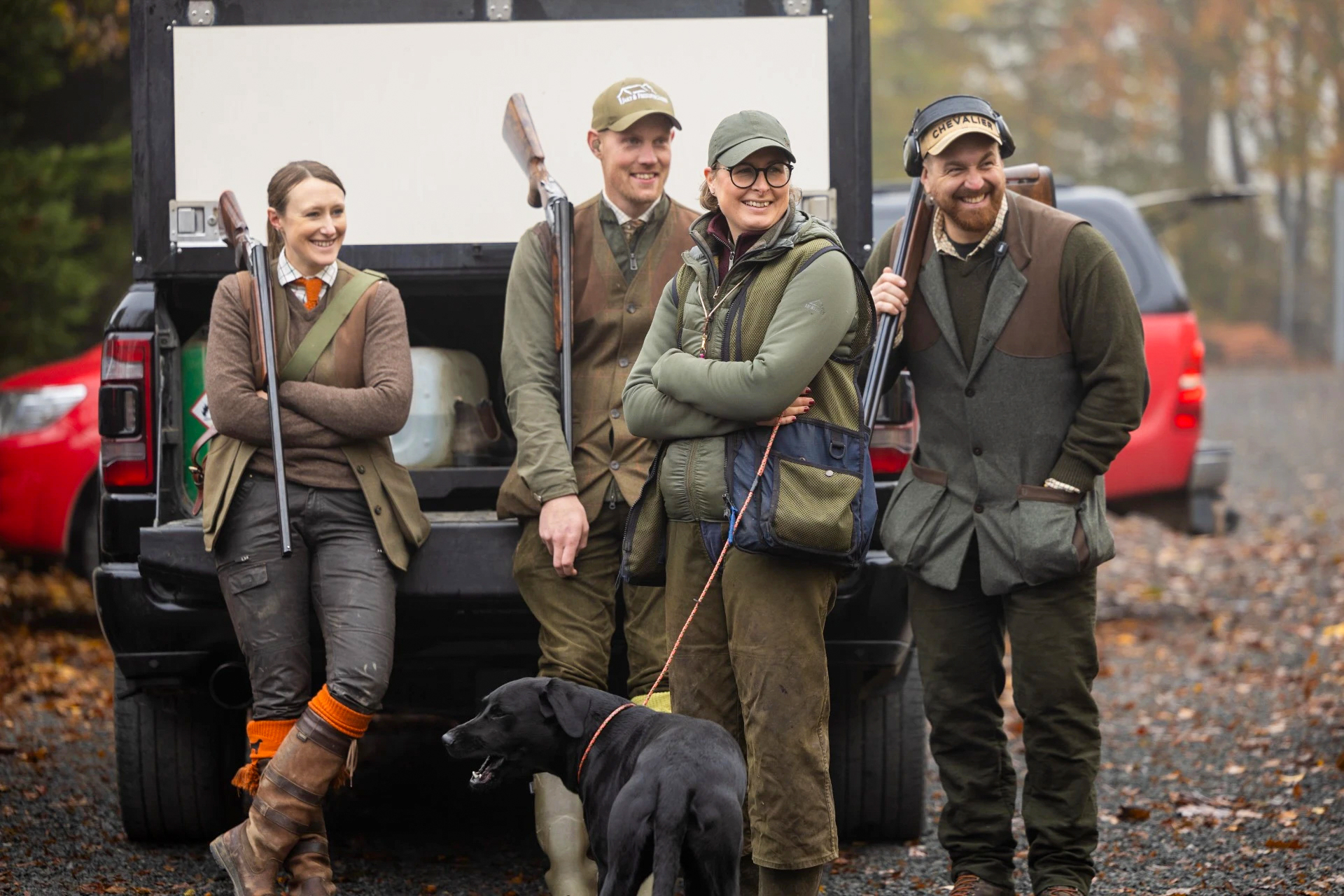 Jägare framför bil med hundar och jaktkläder
